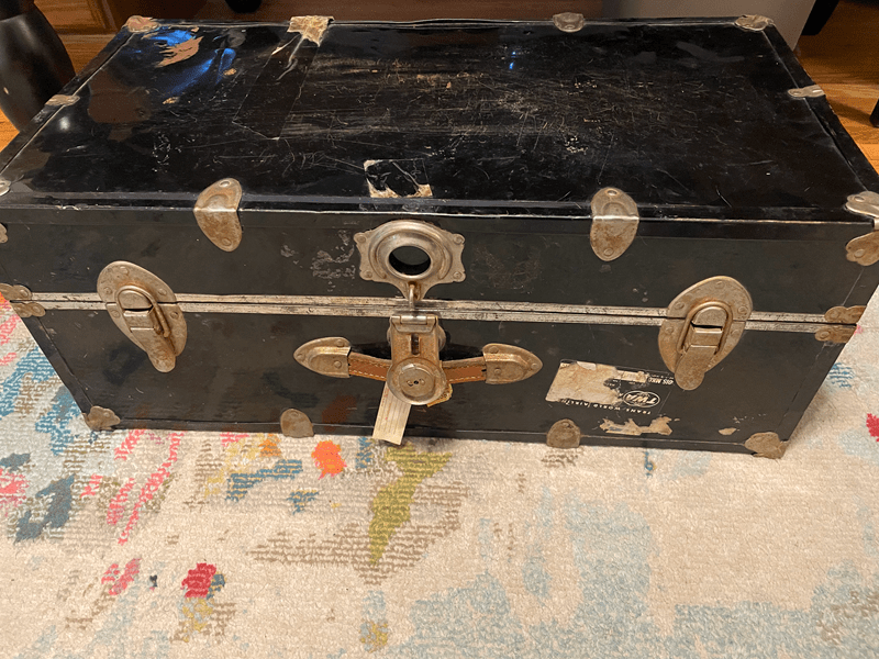 A battered black trunk with gold colored details.